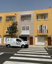 Furgoneta blanca estacionada frente a edificios amarillos en una calle con paso de peatones.
