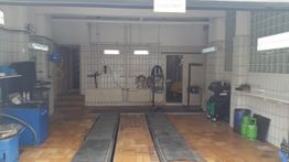 Leere Autowerkstatt mit Hebebühne, blauem Schrank und Werkzeugen an den Wänden.