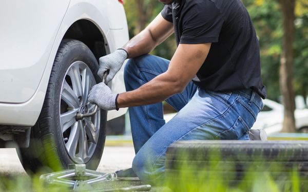 Ein Mann zieht die Schrauben am Reifen seines Autos nach, nachdem er beim Reifenwechsel war.