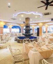 Comedor elegante con mesas blancas, centro de fuente y ventiladores en el techo.