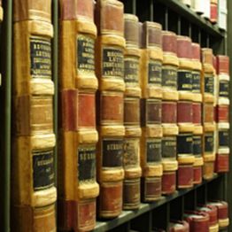 Rows of old, leather-bound books on a library shelf.