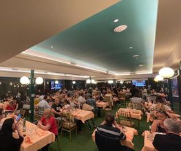 Persone mentre cenano in un grande ristorante affollato con soffitto azzurro.