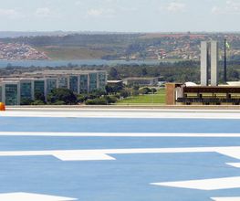 Vista aérea de Brasília com prédios do Congresso Nacional ao fundo e heliporto em primeiro plano.