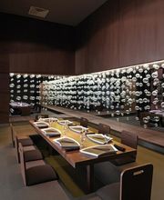 Comedor elegante con mesa de madera, sillas modernas y pared decorada con esferas de vidrio.
