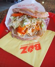 Döner Kebab auf rotem Tablett mit Serviette, gefüllt mit Fleisch, Salat und Soße.