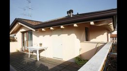 Attico con terrazza, tavolo bianco, pianta e tubo verde sotto un cielo sereno.