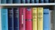 Bunte Fachbücher in einem Regal, geordnet nach Größe und Farbe, mit Schwerpunkt auf Rechtsthemen.