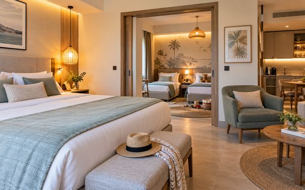 Modernes Familienhotelzimmer mit großem Doppelbett, separatem Kinderzimmer mit zwei Einzelbetten und gemütlichem Wohnbereich mit Sitzmöbeln.