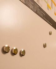 Weiße Magnettafel mit Magneten und einem farbigen Kalender oben rechts.