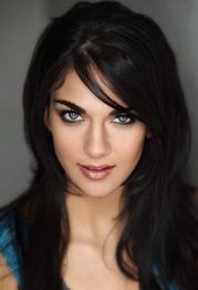 Woman with long dark hair and striking eyes, looking directly at the camera.