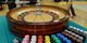 Roulette wheel with multicolored chips on a table, ready for play.