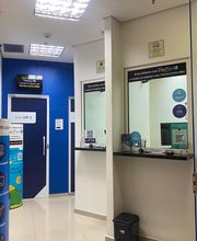 Corredor de loja de câmbio com balcão de atendimento e sinalização em azul e branco.