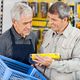 Man assists customer with a product in a hardware store, holding a basket.