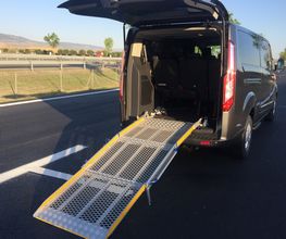 Furgoneta con rampa desplegada para accesibilidad en una carretera bajo cielo despejado.