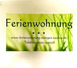 Werbung für eine Ferienwohnung mit Website und Telefonnummer auf grünem Hintergrund.