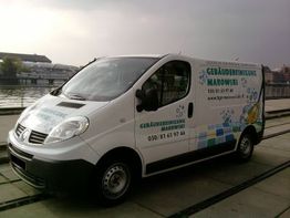 Weißer Transporter einer Gebäudereinigungsfirma, parkend am Wasser bei bewölktem Himmel.