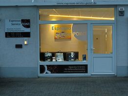 Außenansicht eines Geschäfts mit dem Schild "Espresso Service Point" und Kaffeemaschinen im Fenster.
