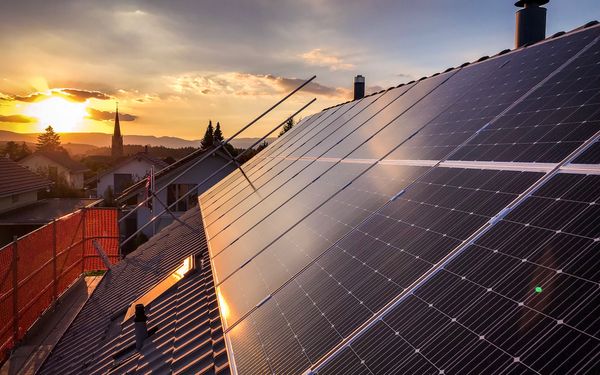 Eine Solaranlage auf einem Mehrfamilienhaus, bei Sonnenuntergang.