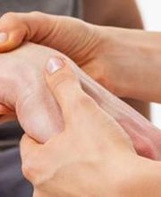 Manos sosteniendo y examinando un brazo en una sesión de terapia o consulta médica.