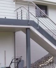 Haus mit Außentreppe und Steingarten, moderne Architektur mit grauen Akzenten.