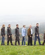 Eine Gruppe von Männern und Jungen steht in einer Linie auf einer Wiese vor einem nebligen Hintergrund.