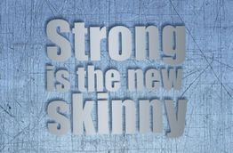 Text "Strong is the new skinny" auf einer blauen, zerkratzten Metalloberfläche.