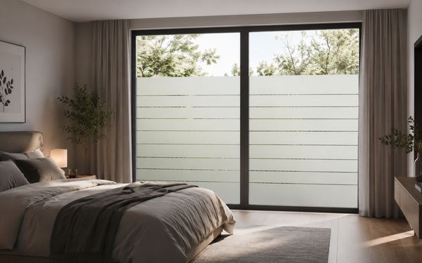 Ein bodentiefes Fenster in einem modernen Schlafzimmer mit Sichtschutzfolie.