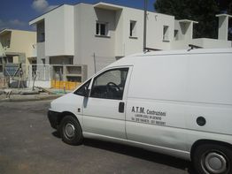 Furgone bianco con iscrizione "A.T.M. Costruzioni" davanti a edifici in costruzione.