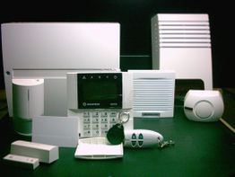 Eine Sammlung von weißen Sicherheitsgeräten auf einem Tisch, darunter ein Tastenfeld und Sensoren.