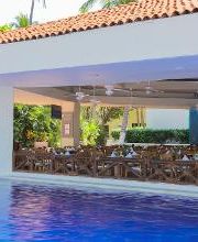 Restaurante abierto junto a una piscina, con mesas preparadas y ventiladores en el techo.