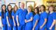 A group of medical professionals in blue scrubs standing together and smiling in an office.