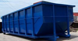 A large blue industrial dumpster sits outdoors on a concrete surface.