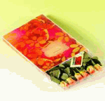 Blumiges Notizbuch auf hellgrünem Hintergrund, darunter Buntstifte in verschiedenen Farben.