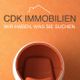 Orange Stuhl vor orangener Wand mit Schriftzug „CDK IMMOBILIEN: Wir haben, was Sie suchen.“