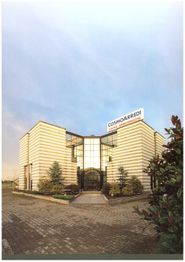 Edificio con pareti a strisce, insegna "Cosmoarredi" e vetrate, circondato da piante.