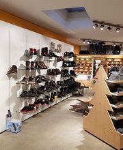 Schuhladen mit Regalen voller Schuhe und Accessoires, Holzausstellungstisch in Tannenbaumform.