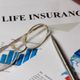 Glasses and pen on a life insurance document with charts and graphs.
