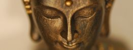 Nahaufnahme eines Buddha-Gesichts aus Bronze mit geschlossenen Augen, ruhiger Ausdruck.