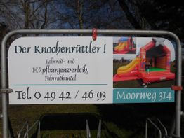 Schild für "Der Knochenrüttler" Fahrrad- und Hüpfburgenverleih mit Adresse und Telefonnummer.