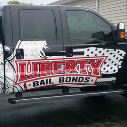 Black truck with a large "Liberty Bail Bonds" ad in red and white on its side.
