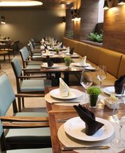 Restaurante elegante con mesas preparadas, vajilla blanca y servilletas dobladas artísticamente.