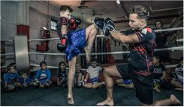Kind tritt in einem Kickbox-Training zu, während andere Kinder zuschauen.