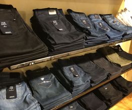 Gefaltete Jeans in verschiedenen Farben auf zwei Regalböden in einem Geschäft.