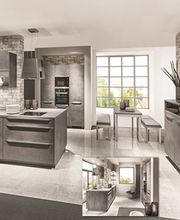 Cucina moderna con mobili grigi, isola centrale e tavolo da pranzo, finestra luminosa sullo sfondo.