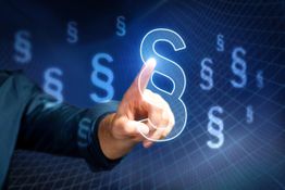 Mensch zeigt auf digitale Paragrafensymbole in blauer Umgebung.