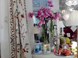 Sala decorada con flores rosadas, cortinas con estampado floral y lámparas brillantes.