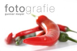 Rote und grüne Chilis auf weißem Hintergrund, mit Text "fotografie gunnar meyer".