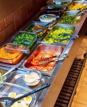 Buffet variado com saladas e vegetais frescos em recipientes de aço inoxidável em um restaurante.