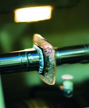 Eje metálico con engranaje cubierto de espuma en ambiente industrial iluminado.