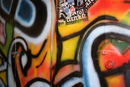 Bunte Graffiti-Wand mit Aufklebern, leuchtenden Farben und geschwungenen Linien.